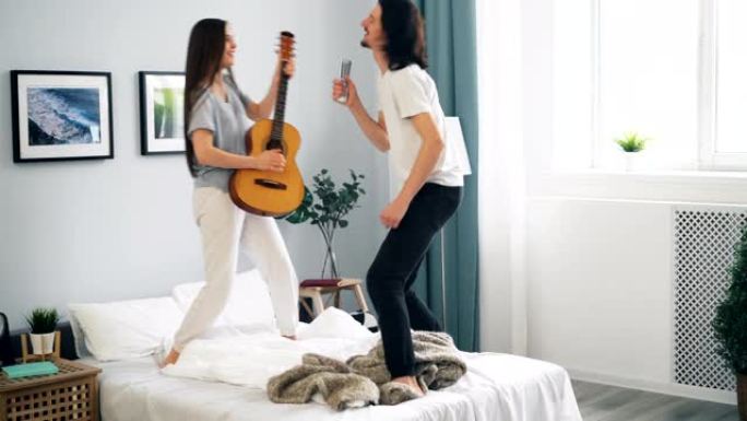 男人和女人玩得开心弹吉他在床上遥控跳舞