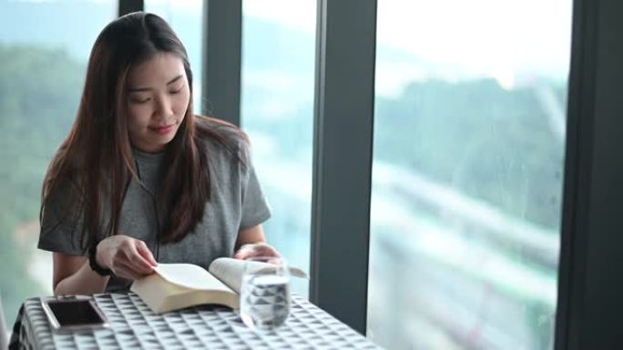 一名亚洲华裔年轻女子在公寓拐角处读书