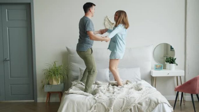 男女夫妇在家里的床上跳舞，享受音乐和关系