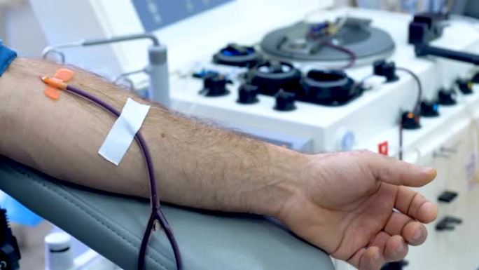 一个男人在诊所献血，输血机工作。