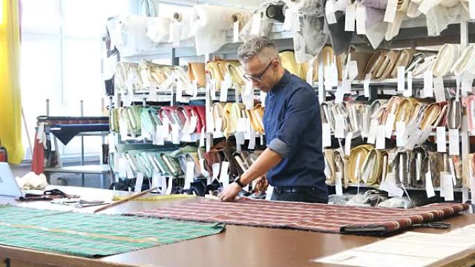 男性裁缝在商店切割格子棉织物