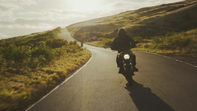 摩托车手在日落时沿着乡间小路骑行