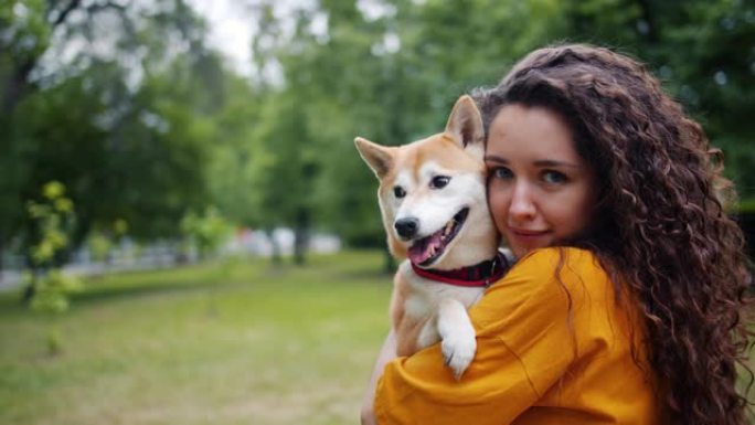 夏天公园里快乐的年轻女子抱着美丽的小狗的肖像