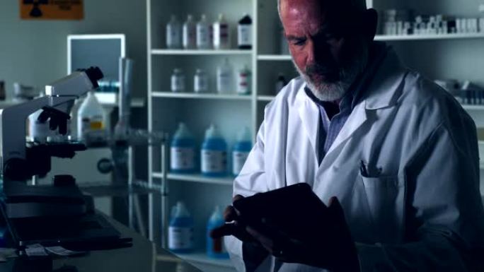 男性科学家在昏暗的实验室中使用数字平板电脑