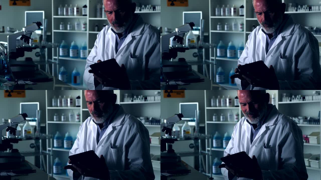 男性科学家在昏暗的实验室中使用数字平板电脑
