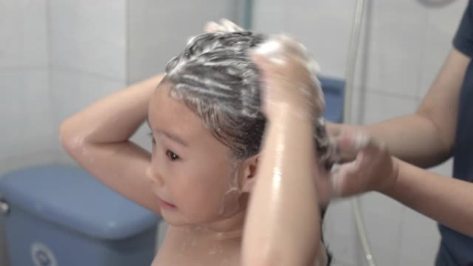 母亲在浴室洗女儿的头发
