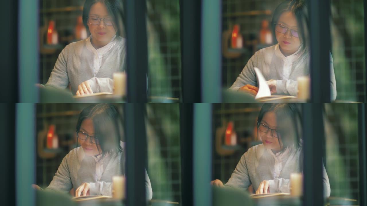 一名亚洲妇女在咖啡馆读书
