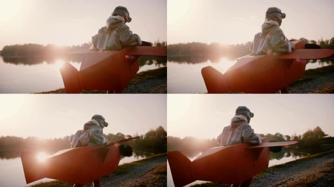 摄像机跟随小快乐的欧洲男孩在日落森林湖慢动作中假装成穿着有趣服装的飞机飞行员