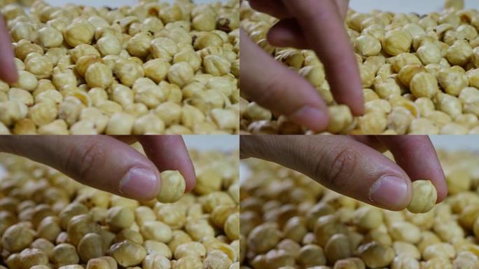 一个男人触摸去皮的浅黄色榛子的特写镜头。概念: 盐渍，坚果，种子，美味，健康，新鲜的产品，适当的营养