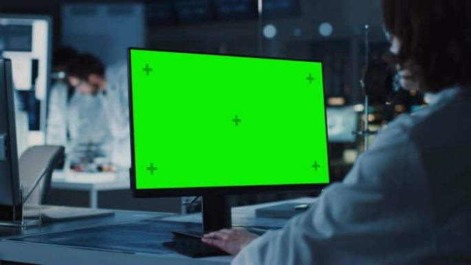 肩膀上的镜头: 女IT科学家使用绿色模拟屏幕计算机。在背景技术研究与开发实验室中，科学家，从事高科技
