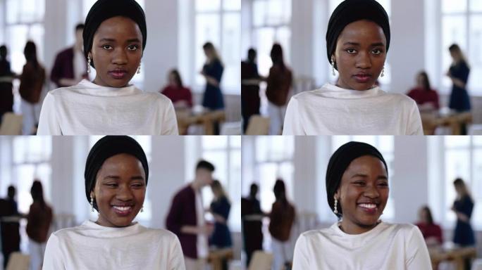 年轻严肃的非洲商业经理女人在种族头巾看着相机，微笑在现代阁楼时髦的办公室。
