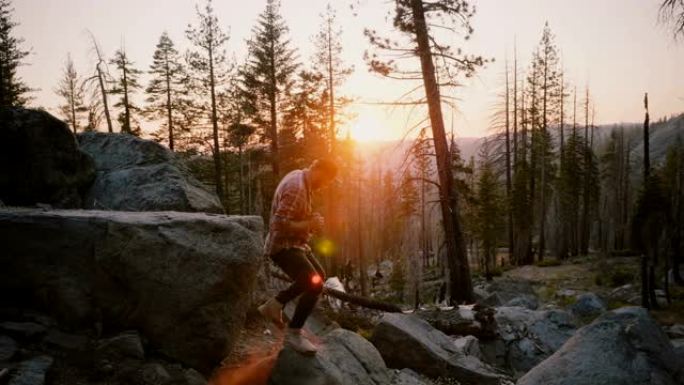成功的年轻男性博主跳下一块大森林石头，在神奇的优胜美地公园日落慢动作上徒步旅行