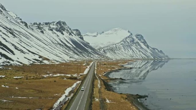 冬季在海边的冰岛公路上行驶的车辆的鸟瞰图