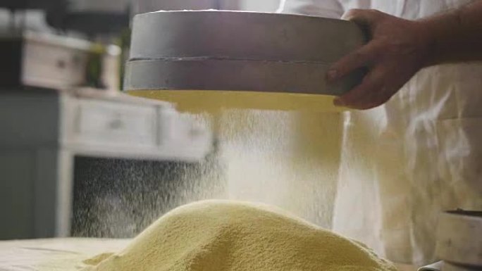 农民的手拿着一把黄色面粉，感受原材料的质量和精髓。