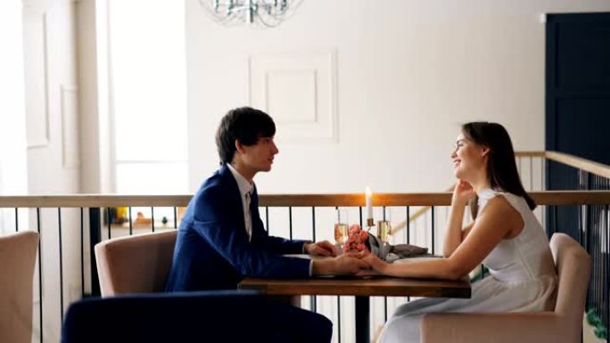 帅哥正在和他的女朋友约会，坐在一起，笑着享受浪漫的时刻和谈话。人和感觉概念。