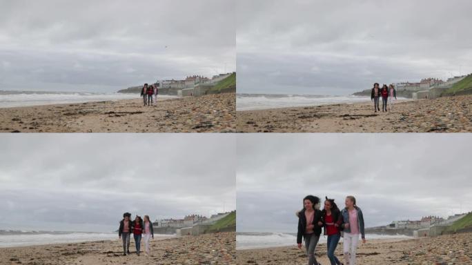 十几岁的女孩沿着多风的海岸散步