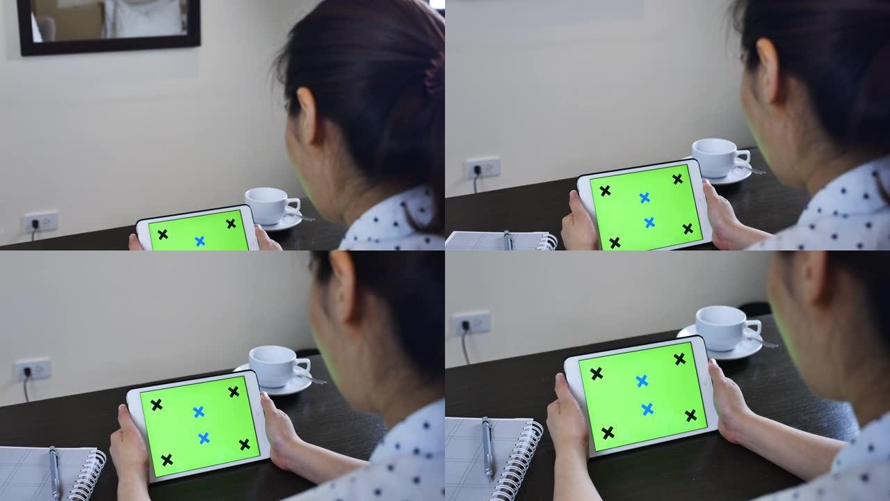 女人在空白的绿色屏幕平板电脑上寻找