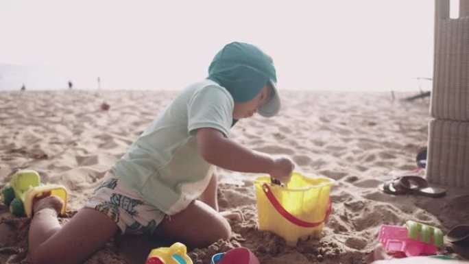 可爱的小男孩在沙滩上玩沙子。泰国。