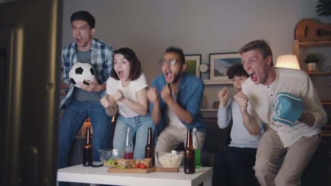 足球迷们在家里的电视上观看比赛，庆祝晚上的胜利