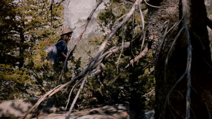 约塞米蒂国家公园森林湖慢动作时，年轻的当地女孩背着背包在美丽的岩石中徒步旅行。