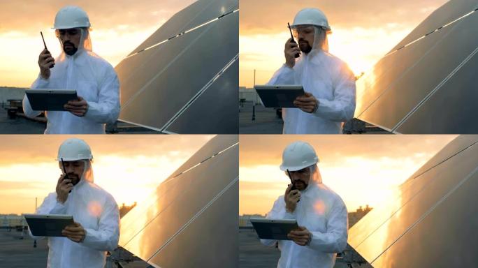 屋顶上的日落景观，男性专家在太阳能电池旁边的发射器上讲话