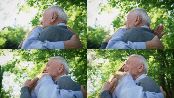 在阳光明媚的日子里，在绿色公园里，快乐孙女的慢动作给了她的祖父一个有效的拥抱，以示爱和尊重
