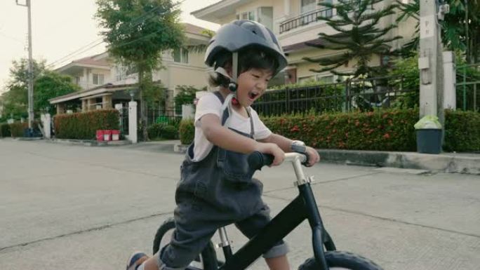 在泰国家附近的晴天，小男孩在外面骑自行车