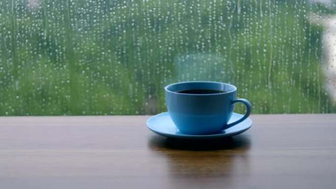 桌上的咖啡杯，雨滴落在窗户上