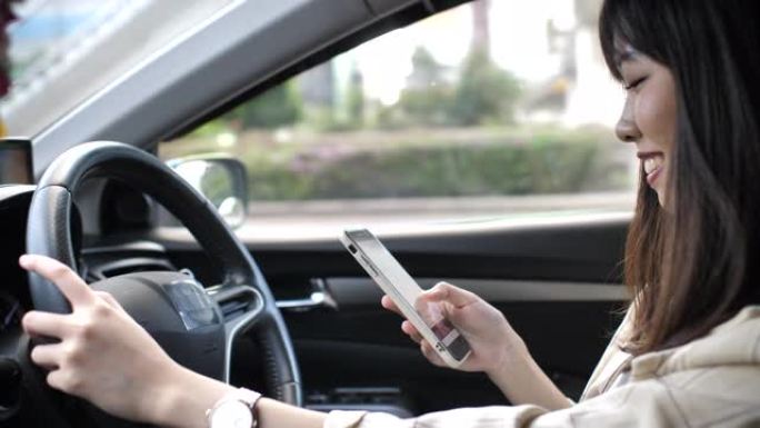亚洲妇女驾驶汽车并在智能手机上键入短信
