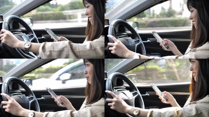 亚洲妇女驾驶汽车并在智能手机上键入短信