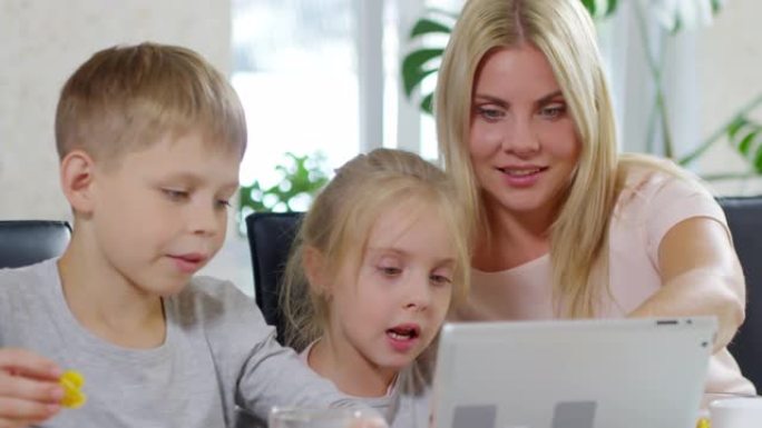 早餐时快乐的孩子和妈妈一起使用平板电脑