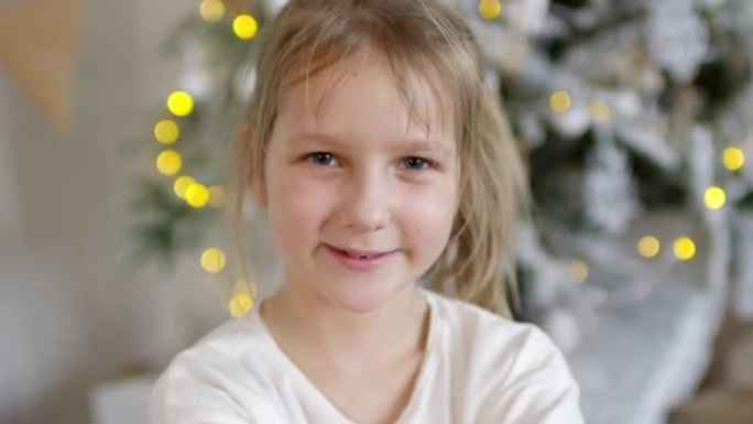 快乐的小女孩在圣诞树附近为相机摆姿势