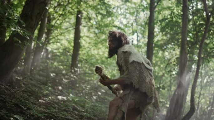 原始穴居人的肖像在史前森林中穿着动物皮和毛皮，用石尖矛狩猎。史前尼安德特人潜入准备将长矛扔进动物体内
