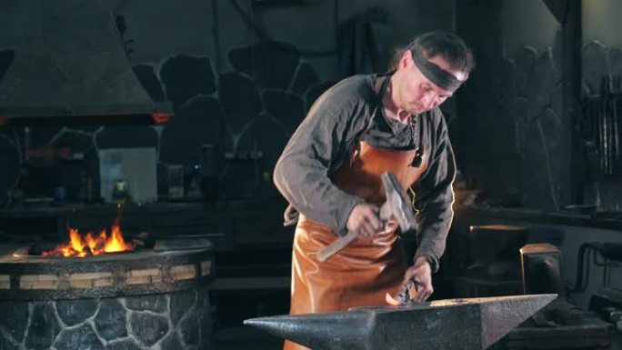 铁匠正在用锤子打铁。慢动作。