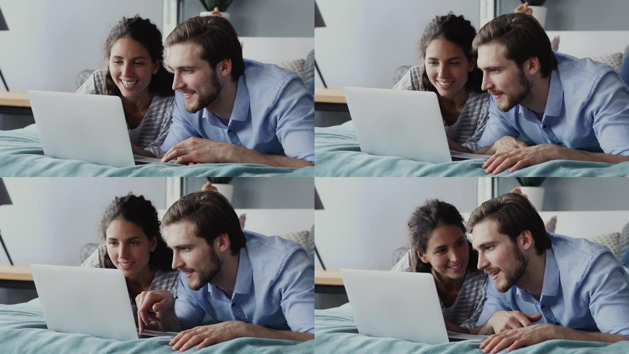 幸福的夫妇使用笔记本电脑观看在线节目躺在床上