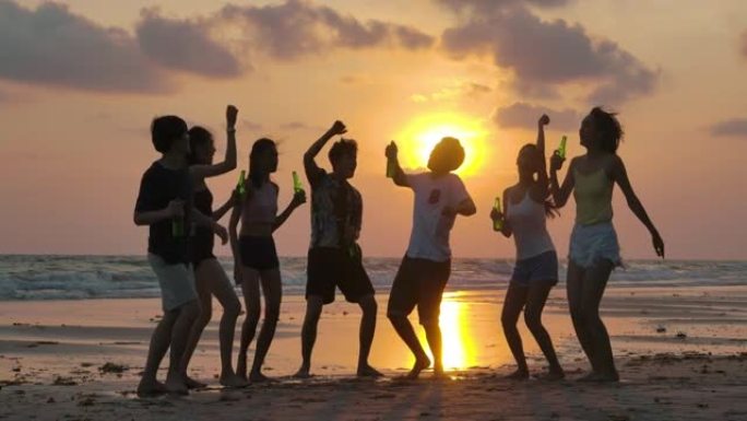 日落时在海滩派对上跳舞的年轻人剪影组的慢动作。