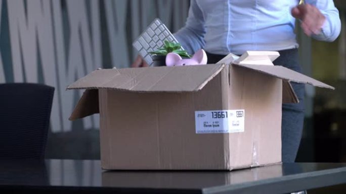 无法识别的女性新员工将一个盒子带到她的办公室并拆开包装