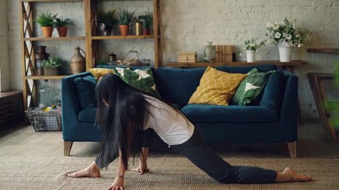 苗条的亚洲女运动员正在坐在地板上在家练习腿部劈腿，然后独自练习时向前弯曲。体操和青少年概念。