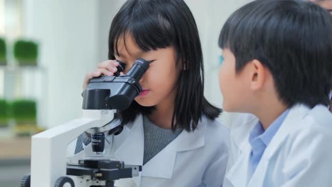 理科学生在学校的实验室里用显微镜看孩子。老师和好奇的学生在教室实验室进行科学实验。教育，技术，团队合