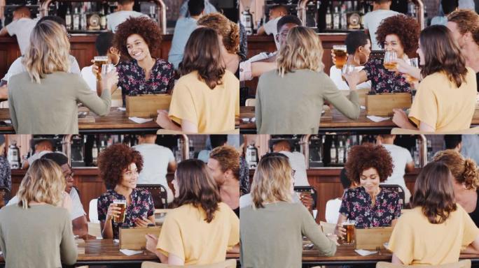 一群年轻朋友在餐厅酒吧见面时用啤酒敬酒-慢动作拍摄