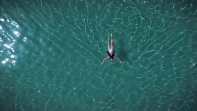 夏天，海滩上的一位美女在平静的海水中放松，海水清澈透明。