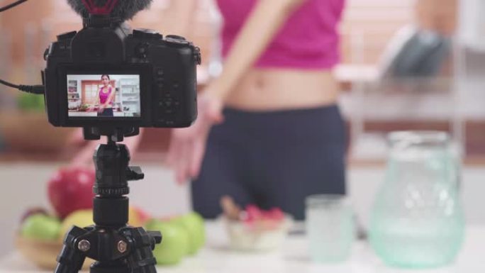 亚洲博主女人制作vlog如何节食和减肥，年轻女性在厨房吃酸奶时使用相机录音。生活方式影响者女性健康理