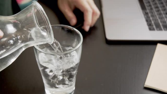 亚洲男子通过在笔记本电脑上键入业务订单在工作时倒水和喝水