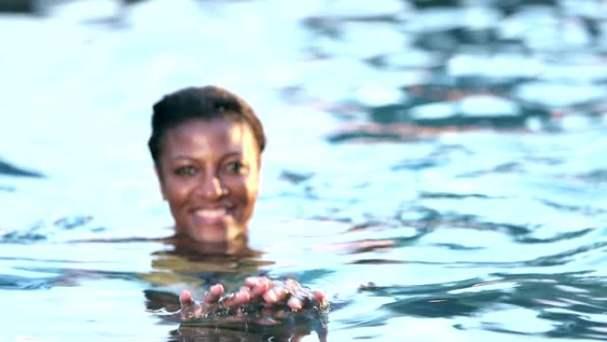 游泳池中的成熟非裔美国妇女走向相机
