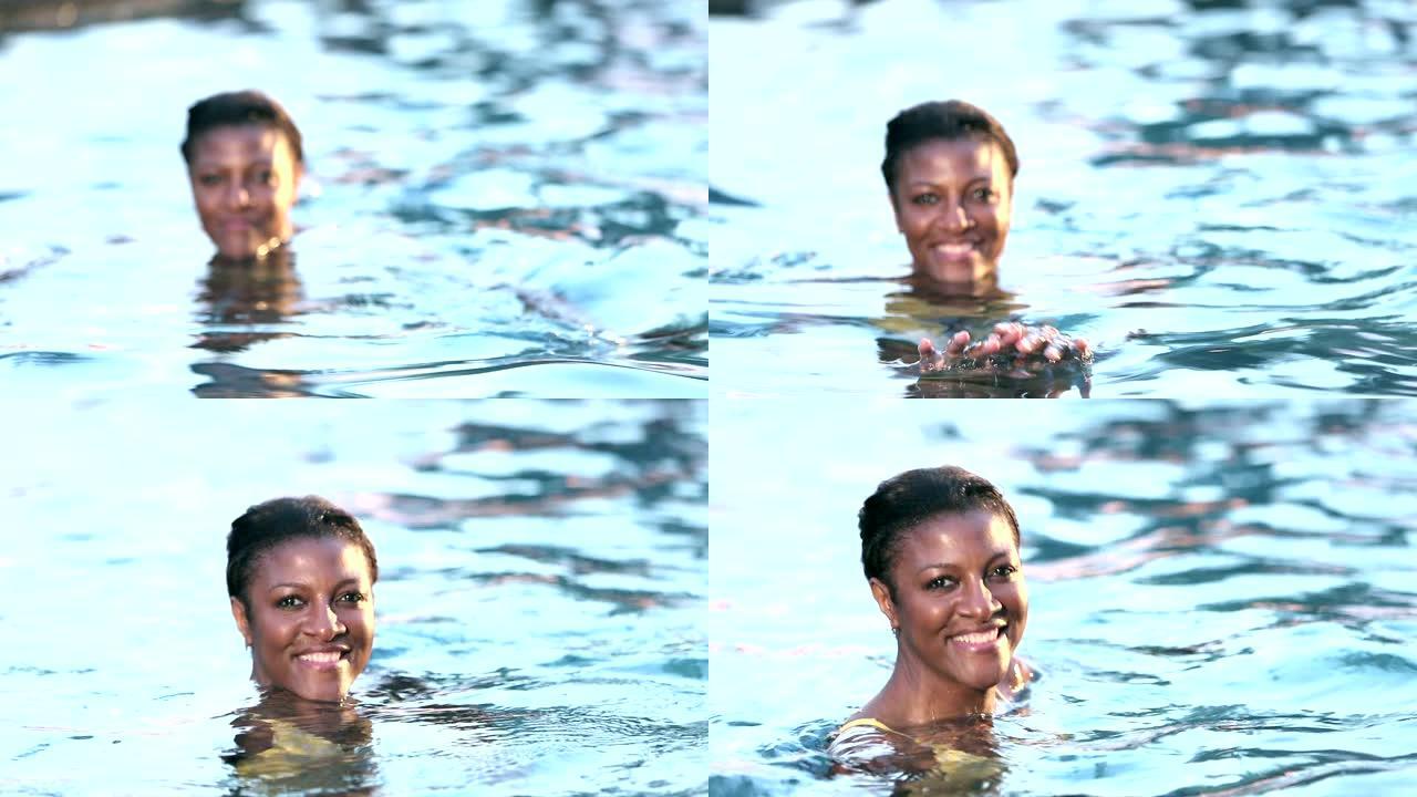 游泳池中的成熟非裔美国妇女走向相机