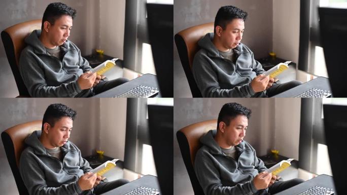 一名亚洲华裔中年男子下午在其家庭办公室看书