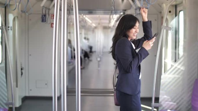 年轻的亚洲女商人在公共交通中使用智能手机