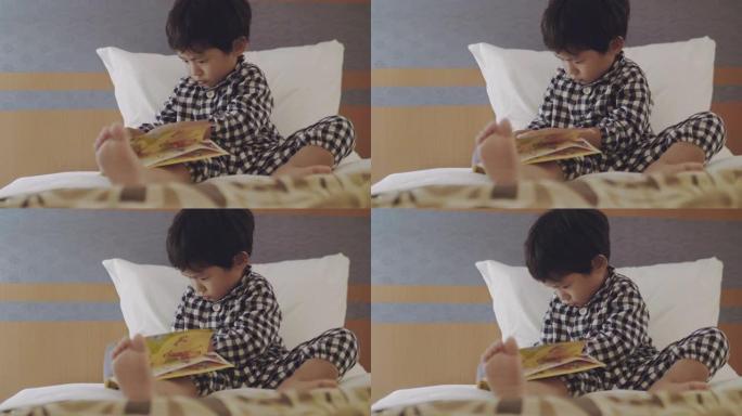 亚洲小男孩晚上在床上看书。
