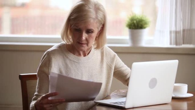 微笑的老成熟女士在笔记本电脑上在线支付账单