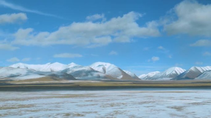 乘坐火车时，西藏积雪覆盖的平原和山脉的壮丽景色